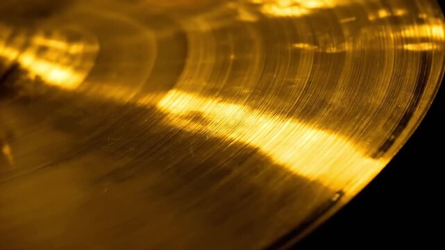 Close-up of a shiny brass cymbal with dramatic lighting and texture.