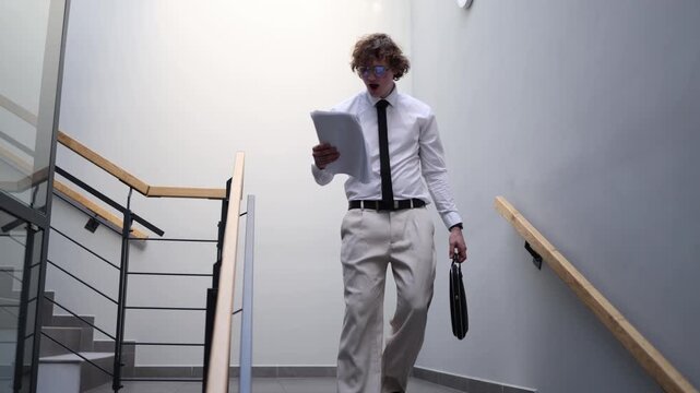 Businessman reacts to failed plan reviewing documents on stairwell looking frustrated and overwhelmed by results reflecting stress pressure and disappointment in modern work environment