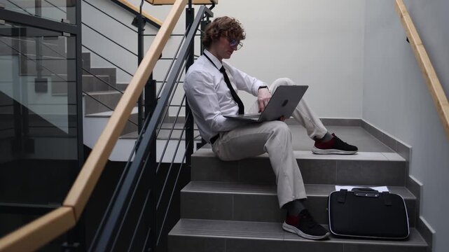 Stressed developer struggling with project on laptop sitting on office stairs problem solving difficulty deadline pressure frustration at work coding challenge mental overload