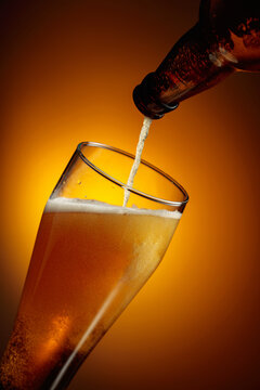 Pouring beer into a tall glass.