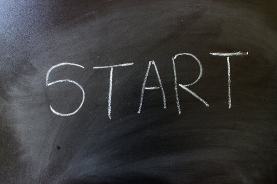 "START" Handwritten in White Chalk on a Blackboard for New Beginnings