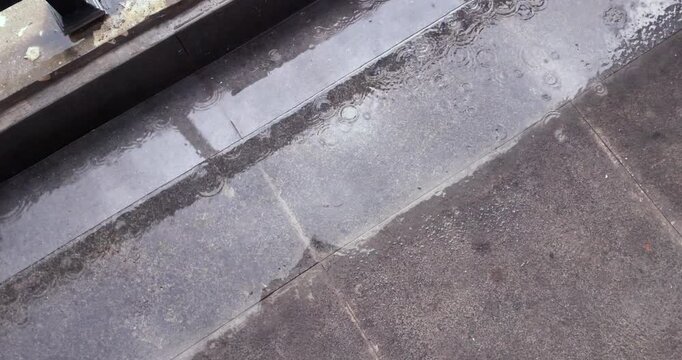 Slow motion  of raindrops falling on wet stone steps, creating ripples and bubbles