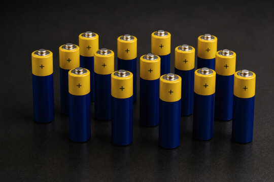 Minimal AA batteries lineup on dark background, power supply and energy concept