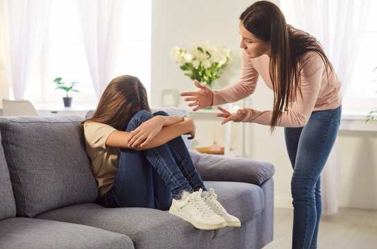 Teenage girl hiding face, mother, teen daughter conflict at home, scolding grown up child, angry mum feeling stressed, misunderstandings, generational gap, difficulties in relationships, disagreement