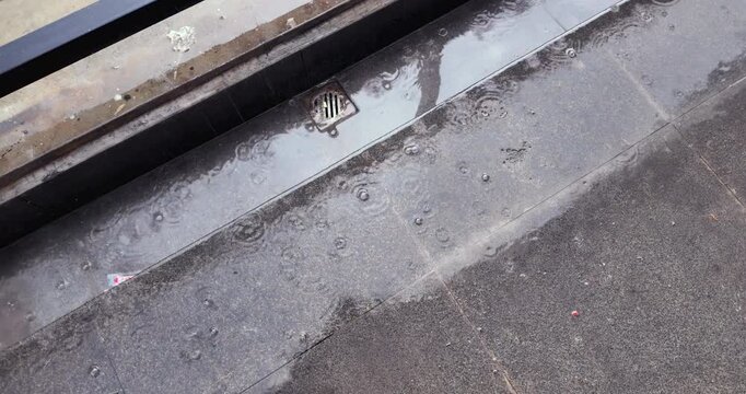 Close up of raindrops creating ripples on wet stone steps
