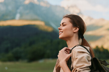 Naklejka premium A woman in outdoor gear enjoys a sunny hike, backpack secured, as rugged mountains rise in the background. A calm moment for wellness, exploration, and everyday adventure.