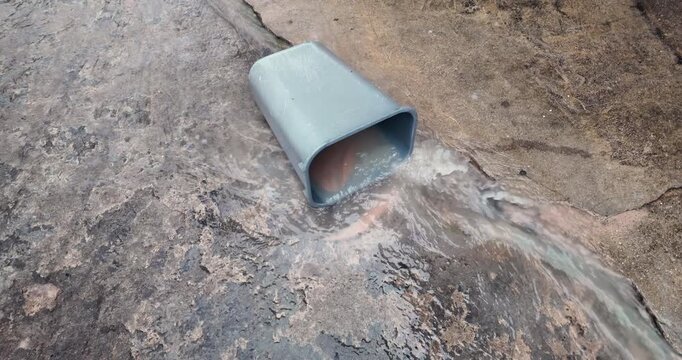 slow motion of a grey plastic bin in a flash flood. Turbulent muddy water rushes into the container on rough concrete, capturing authentic fluid dynamics, eddies, and splashes in an urban environment