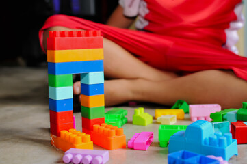 Fototapeta premium Close-up of a child’s hands playing with colorful building blocks (LEGO-style toys). The image highlights creativity, learning through play, and fine motor skill development in early childhood. Bright