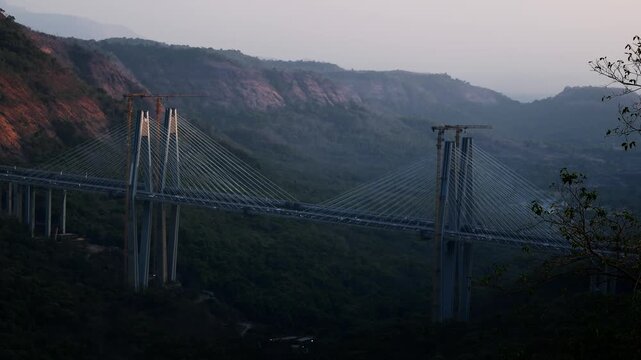 Daytime timelapse of the Mumbai&ndash;Pune Missing Link bridge section on the expressway, showcasing modern highway infrastructure cutting through hilly terrain.