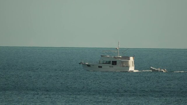 Motor yacht, ocean, boating: A white vessel with a dinghy navigates calm, tranquil seas, symbolizing leisure travel and freedom
