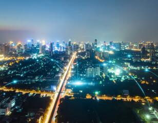 Obraz premium An aerial view showcases a sprawling cityscape illuminated at night, connected by glowing lines symbolizing digital networks and modern infrastructure.