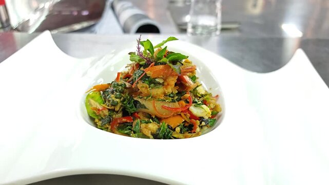 Gourmet Thai spicy stir-fried shrimp with herbs and fingerroot in a modern white plate.