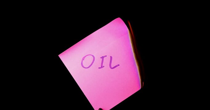 Pink post it note with oil text burning on black background symbolizing the end of fossil fuels and the rising energy market crisis.