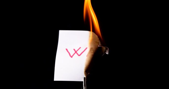 White post it note with war text burning on black background symbolizing the end of armed conflict and the destruction of battle.