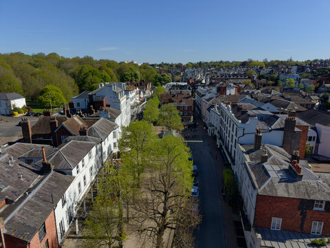 Aerial view of historic Pantiles at Royal Tunbridge Wells in springtime. Directly above the street with restaurants, shops and outdoor sitting under the green trees. Quiet sunny day in springtime.