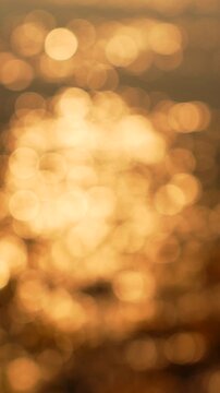 Bokeh water sunlight sparkles on the vertical surface of the ocean during a warm sunset creating a beautiful out of focus background