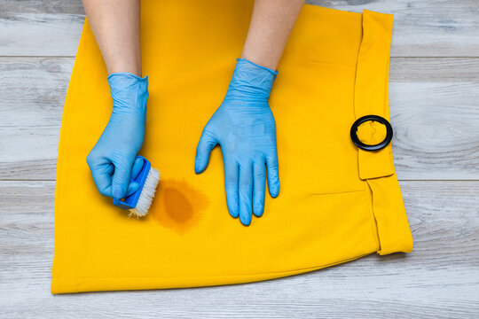 A woman removes a stain from her skirt. A woman's hand holds a stain remover to remove a dirty spot from a skirt. 
