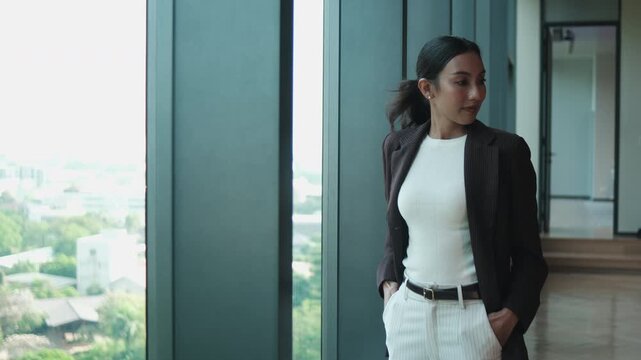 One young, attractive Asian businesswoman in suit, using mobile phone for business report summary at modern workplace hall before meeting, financial job, and technology communication, urban lifestyle.
