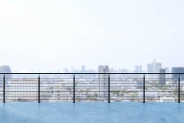 Obraz premium Modern rooftop terrace with sleek metal railing overlooking a softly blurred city skyline under bright light, creating an open urban backdrop and calm rooftop atmosphere. 3D Rendering