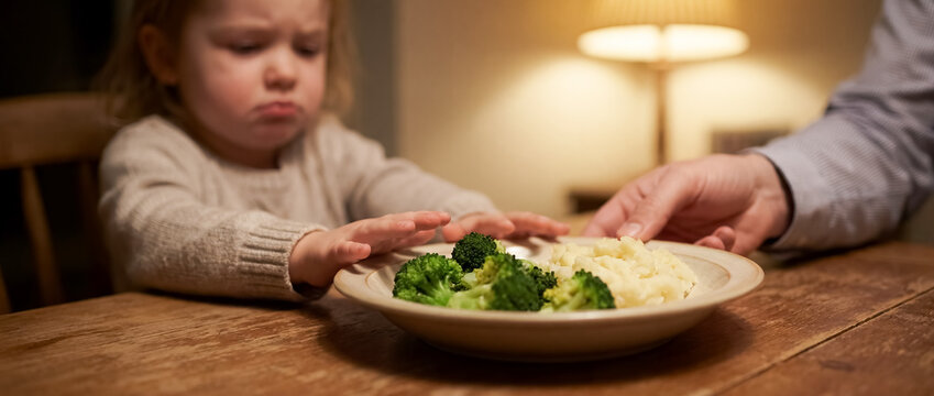 child food refusal family dinner behavior challenge mealtime stress closeup with upset kid pushing away vegetables while adult offers plate showing nutrition conflict parenting patience and support