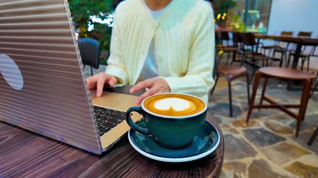 Woman hands and fingers typing on grey laptop, computer. Next to her coffee. Working, studying. 