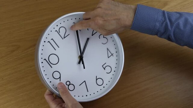 Change the time clocks hour 2 to hour 3. Man's hand moves the hand to change the time