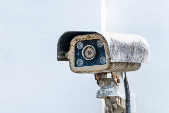 Old surveillance security camera mounted on wall, monitoring and protection system, worn equipment and aging technology, safety, control and privacy concept with copy space