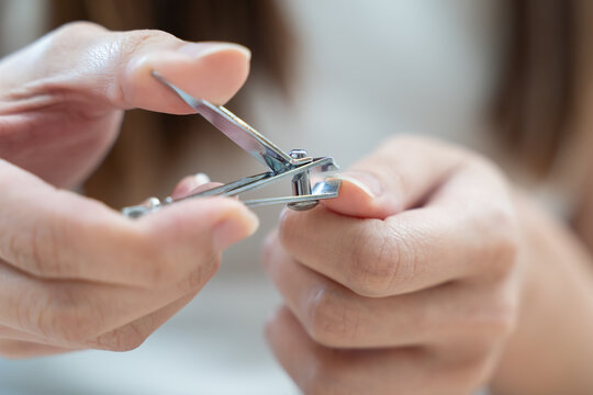 young woman hand manicure with nail clipper cutting fingernail on long or dirty finger