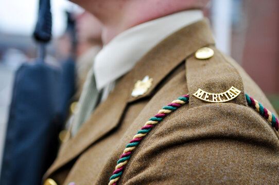 Soldiers of the 2nd Battalion, The Mercian Regiment, stand in disciplined formation with assault rifles during a formal military parade, dressed in multi-terrain pattern camouflage and berets.