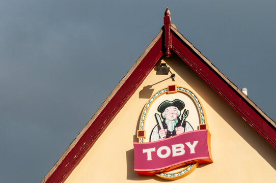 The illuminated rooftop sign depicting a Toby Jug character on the gable end of a Toby Carvery restaurant