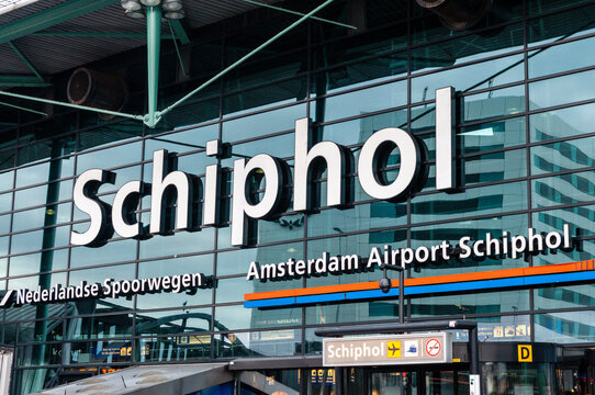 Main entrance facade of Amsterdam Airport Schiphol, showcasing modern glass and steel architecture with signage, signaling a busy international travel hub in the Netherlands.