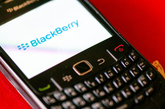 A classic Blackberry Curve 8700 handheld smartphone, featuring its iconic QWERTY keyboard and navigation trackwheel, displayed on a clean surface.