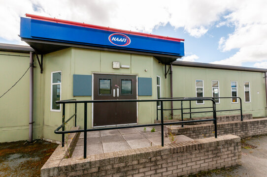 A modest, NAAFI canteen serving as a communal hub on a military base, capturing the utilitarian aesthetic and nostalgic atmosphere of mid-20th-century service life.