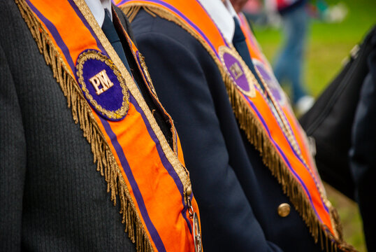 Two Past Masters of the Orange Lodge stand while wearing their sashes collarettes.