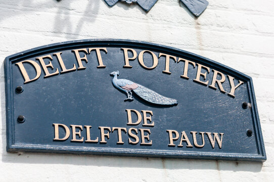 A weathered, vintage-style sign marks the entrance to a historic Delft pottery workshop in the Netherlands, capturing the timeless essence of the city's world-renowned blue and white ceramic tradition