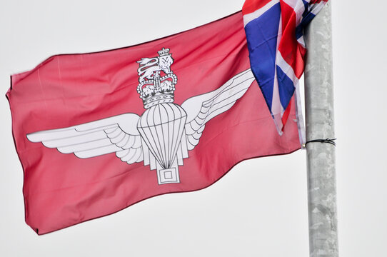 The maroon flag of the British Army's Parachute Regiment flies alongside the Union Jack on a row of street lampposts