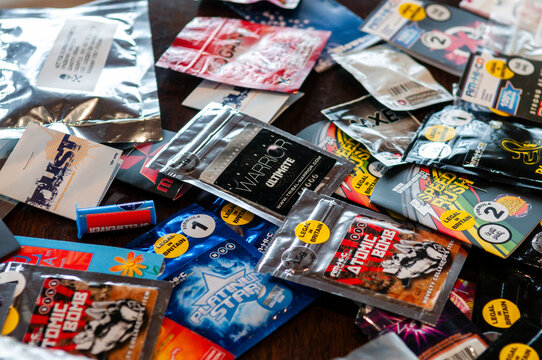 A diverse collection of branded "legal high" packets and sachets, featuring colorful packaging for synthetic psychoactive substances like Atomic Bomb and Speed Rush, sold as research chemicals.
