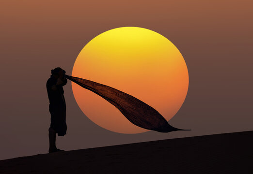 A Muslim man praying on the sand in the desert at sunset - Sahara, Morocco