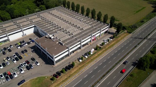Industrial Warehouse Next to Highway: An aerial view showcases a large industrial warehouse complex situated alongside a busy highway, highlighting urban development and logistics infrastructure.