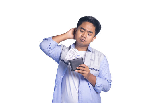 A sad young man scratching his head while looking down at a black wallet with dollar bills on a white background.