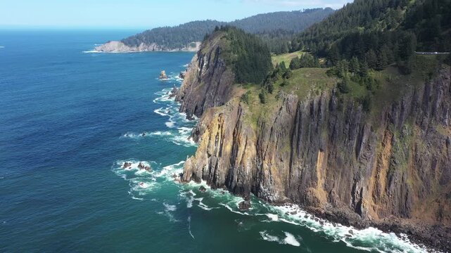 4K aerial drone footage of rugged cliffs and ocean waves along the Oregon Coast near Elk Flats Trail with Cape Falcon visible in the distance, West Coast USA. Scenic Pacific Ocean shoreline landscape 