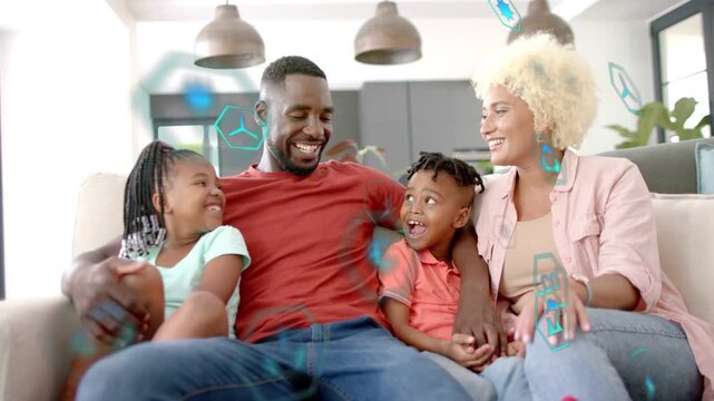 Family bonding on sofa, father turning to son causing smiles, cyan hex tech icons crossing frame