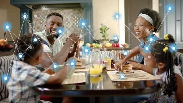 Family of four sitting table, father reaching causing tech nodes linking pancakes, glasses, people