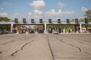 Obraz premium Multi lane toll road entrance with electronic signs showing speed limits and fees, vehicles approaching payment booths on busy highway, road infrastructure and commuter transport concept