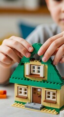Naklejka premium Child playing with toy house blocks.