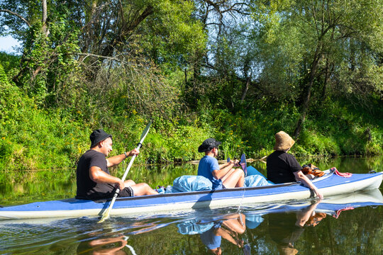 Parents and child paddling the Vuoksa kayak on a calm river, family water trip, teamwork, active summer recreation and healthy leisure.
