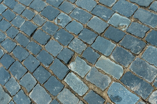 Cobblestone pavement texture top view. Ancient stone blocks of a city street road surface. Grey granite sett stones pattern for architectural background