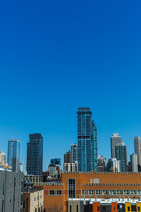 Fototapeta premium City skyline shows tall buildings under clear blue sky during daytime in a busy urban area