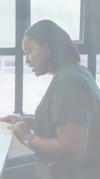 Vertical video: Woman holding doc by grid window reading then lifting head and speaking sales pitch