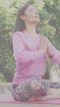 Vertical video: Woman doing yoga on pink mat inhaling lifting chest and opening palms for wellness